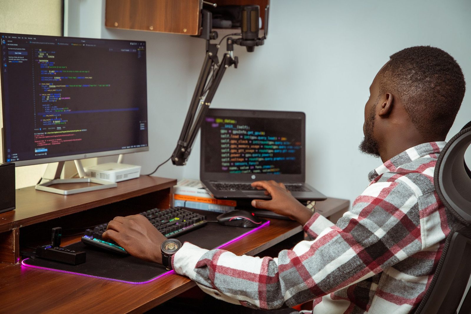 Software developer writing code across two screens